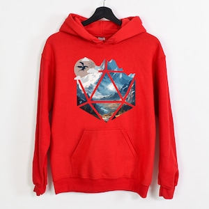 Pode incluir: Camisola de capuz vermelha com uma estampa gr&aacute;fica de uma paisagem montanhosa dentro de uma forma geom&eacute;trica, que se assemelha a um dado.