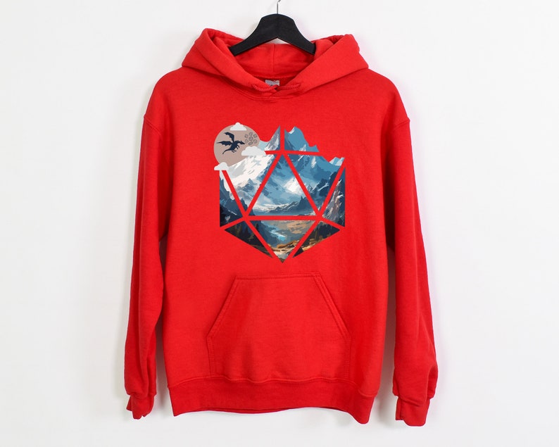 Pode incluir: Camisola de capuz vermelha com uma estampa gr&aacute;fica de uma paisagem montanhosa dentro de uma forma geom&eacute;trica, que se assemelha a um dado.