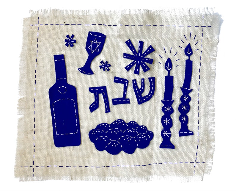 May include: Blue fabric with a stitched design of a wine bottle, a glass, a menorah, a star of David, and the Hebrew word "Shabbat" on a white background.