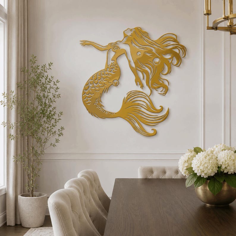 Puede incluir: Una pieza de arte mural de metal en color dorado que representa a una sirena con cabello largo y fluido y una cola detallada. La silueta muestra a la sirena en una pose de nado con los brazos extendidos hacia arriba y detalles recortados.