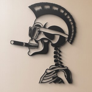 May include: Black and white paper cut-out of a skull with a mohawk, sunglasses, and a cigarette. The skull is wearing a skeleton body.