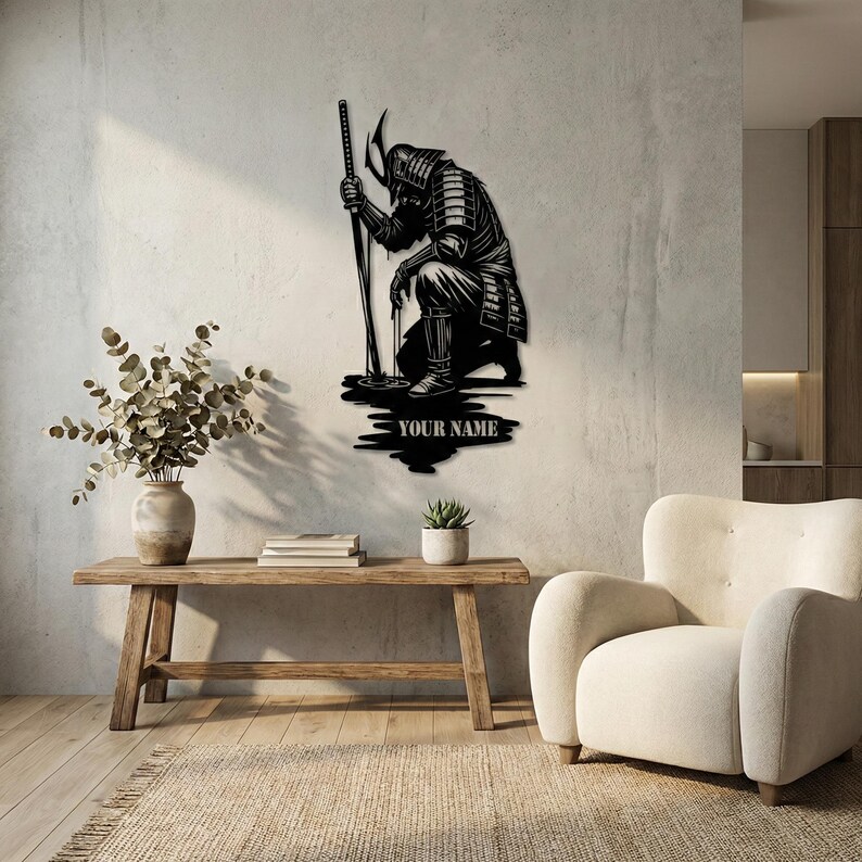 May include: Black metal wall art depicting a kneeling samurai warrior holding a katana. The artwork includes the text "YOUR NAME" at the base. The samurai is wearing traditional armor and a helmet. The art is mounted on a light-colored wall.