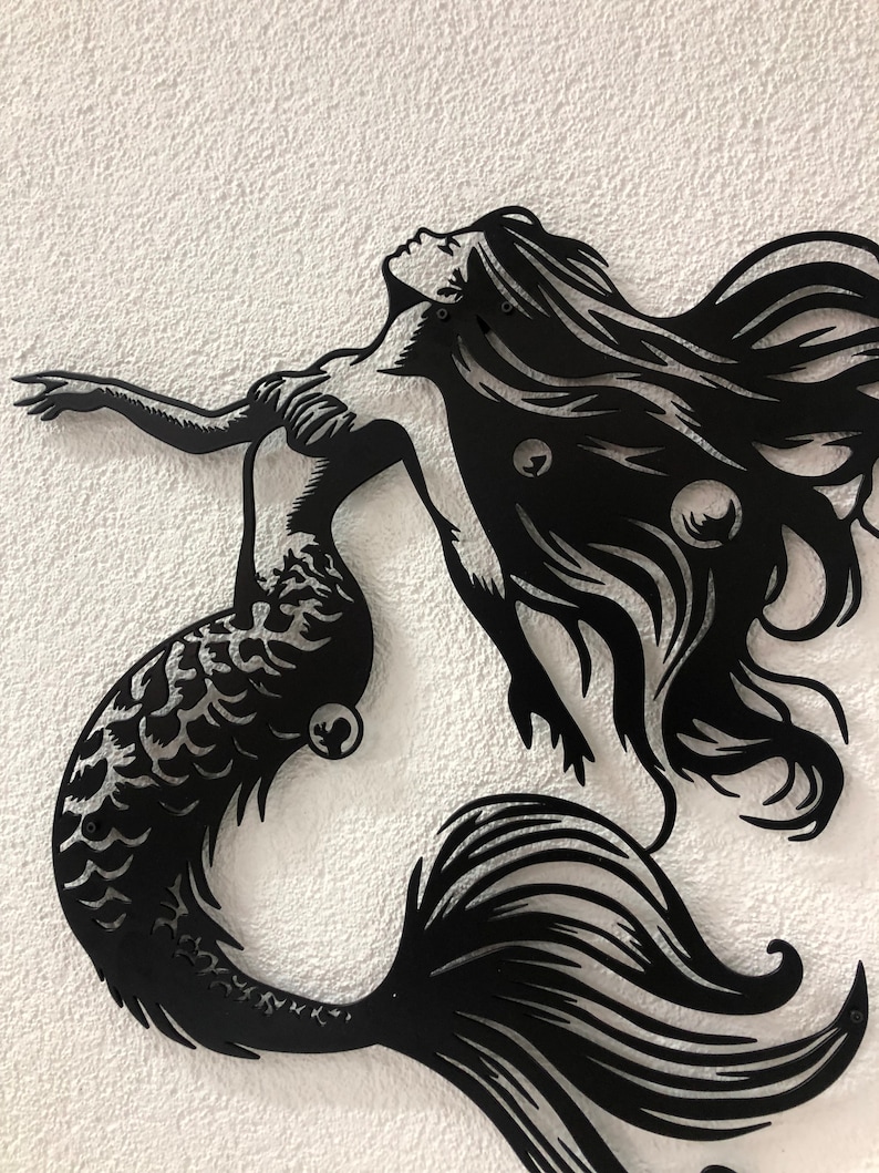 Puede incluir: Una pieza de arte mural de metal negro que presenta la silueta de una sirena con cabello largo y fluido, espalda arqueada y un brazo extendido. El dise&ntilde;o incluye recortes intrincados que representan escamas en la cola y burbujas.