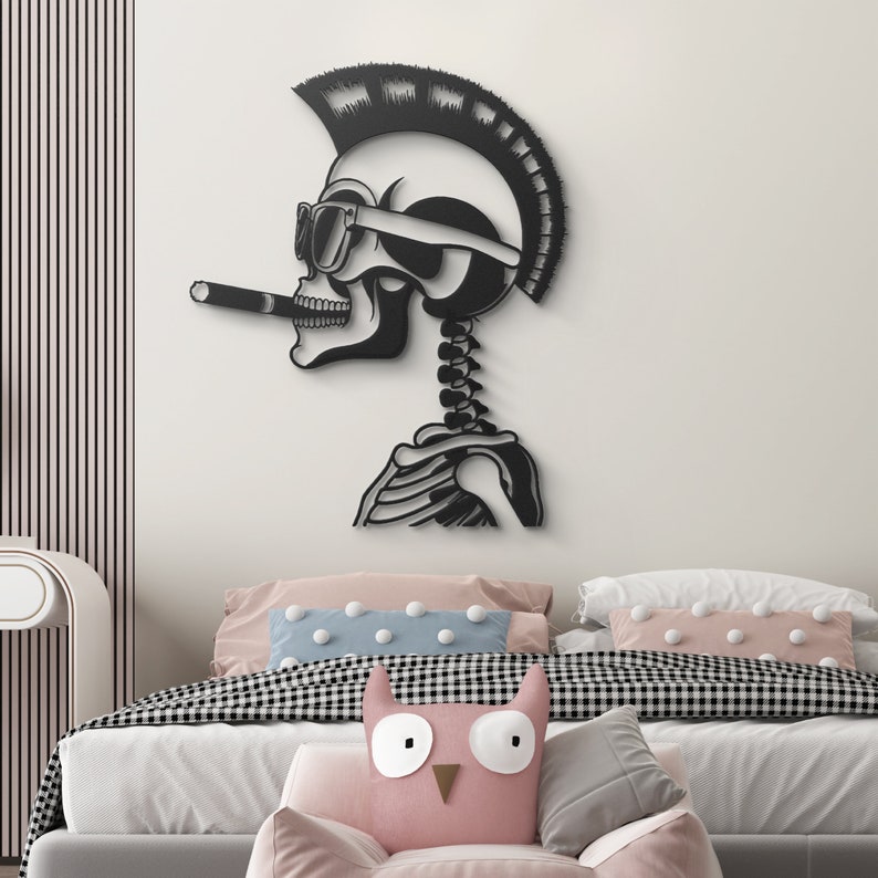 May include: Black and white wall decor featuring a skeleton with a mohawk, sunglasses, and a cigarette. The skeleton is in a relaxed pose with its arms crossed. The decor is mounted on a white wall above a bed with pink and blue pillows.