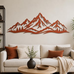 May include: A wide, rust-colored metal wall art piece depicting a jagged mountain range with sharp peaks and a forest of pine trees along the base. The design features cut-out details that create a layered, silhouette effect across the wall.