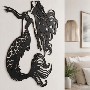 Puede incluir: Una pieza de arte mural de metal negro que presenta la silueta recortada de una sirena con cabello largo y fluido y una cola detallada. El dise&ntilde;o muestra a la figura extendiendo un brazo hacia arriba, con recortes intrincados en el cuerpo.