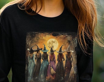 May include: Black long-sleeve shirt featuring a graphic of witches under a full moon with the text "Witches gotta stick together." The shirt is a Bella Canvas 3501 Black.