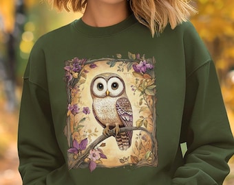 May include: A green sweatshirt with an owl illustration on the front. The owl is surrounded by flowers and leaves. The text "Gildan SF000 Military Green" is at the bottom of the image.