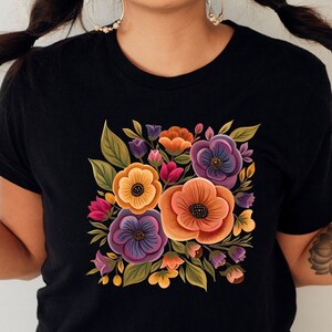 May include: Black t-shirt with a colorful floral print featuring orange, yellow, purple, and green flowers.