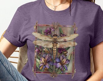 May include: A purple heather Bella Canvas t-shirt featuring a dragonfly with gold wings and purple flowers in a gold frame. The shirt is a unisex style.
