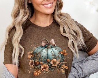 May include: A brown t-shirt with a blue and green pumpkin with fall leaves and flowers. The text "Bella Canvas Heather Brown" is in the bottom right corner of the image.