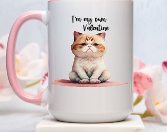 May include: White ceramic coffee mug with a pink rim and handle. The mug features a cartoon illustration of a white and orange cat with the text "I'm my own Valentine".
