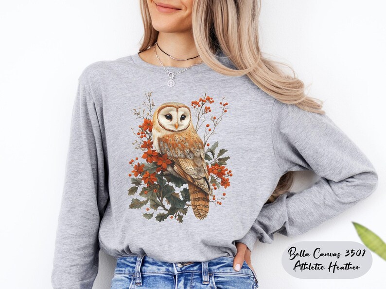 May include: A gray long-sleeve shirt with a white barn owl perched on a branch with red berries and green leaves. The shirt is Bella Canvas 3501 Athletic Heather.