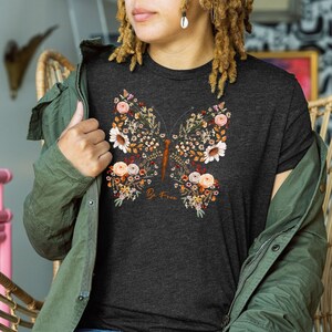 May include: A dark heather grey t-shirt with a floral butterfly design and the text "Be Free".