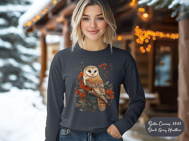 May include: A dark grey heather Bella + Canvas 3507 long-sleeve shirt with a white barn owl perched on a branch with red berries. The owl has a white face and brown and white feathers.