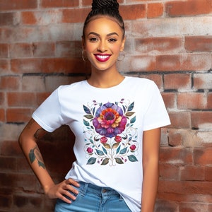May include: A white t-shirt with a colorful floral design featuring a large flower with pink, purple, and orange petals. The design is surrounded by green leaves and vines.