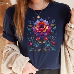 May include: A navy blue t-shirt with a colorful floral design. The design features a large flower with pink, purple, and orange petals, surrounded by smaller flowers and leaves.