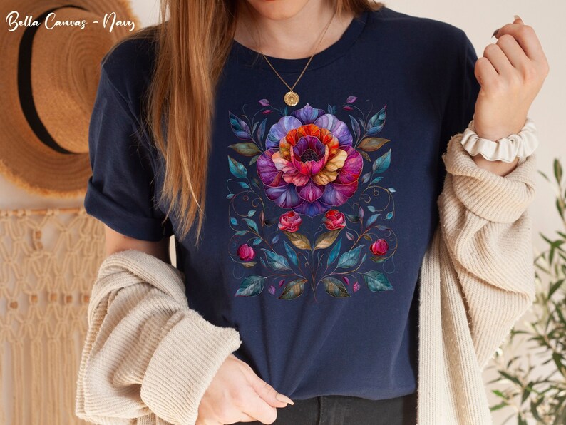 May include: A navy blue t-shirt with a colorful floral design. The design features a large flower with pink, purple, and orange petals, surrounded by smaller flowers and leaves.