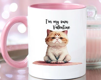 May include: White ceramic mug with a pink rim and handle. The mug features a cartoon illustration of a cat with the text "I'm my own Valentine".