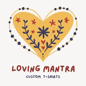 May include: A yellow heart with a floral design in red, blue, and white. The heart is surrounded by a blue dotted line. The text "LOVING MANTRA CUSTOM T-SHIRTS" is below the heart.