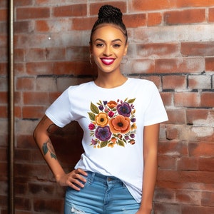 May include: A white t-shirt with a colorful floral print featuring orange, yellow, purple, and green flowers. The flowers are arranged in a square shape on the front of the shirt.