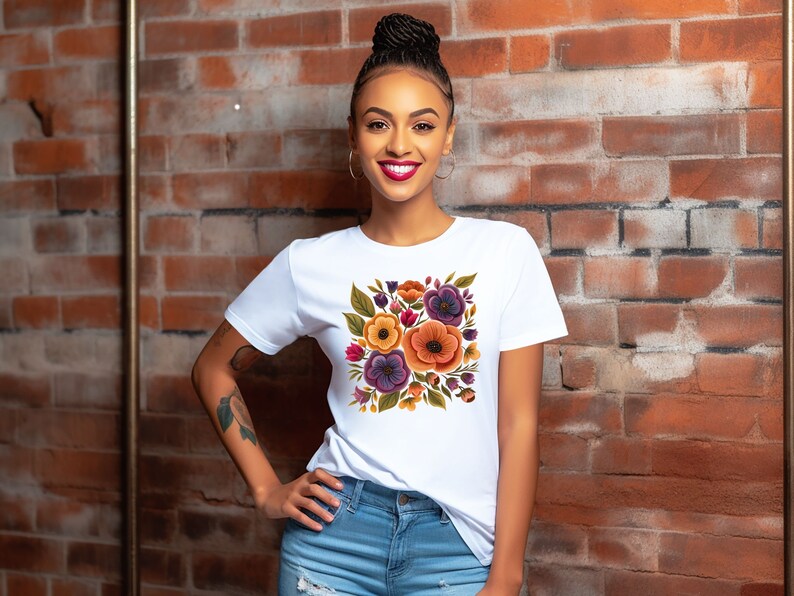 May include: A white t-shirt with a colorful floral print featuring orange, yellow, purple, and green flowers. The flowers are arranged in a square shape on the front of the shirt.