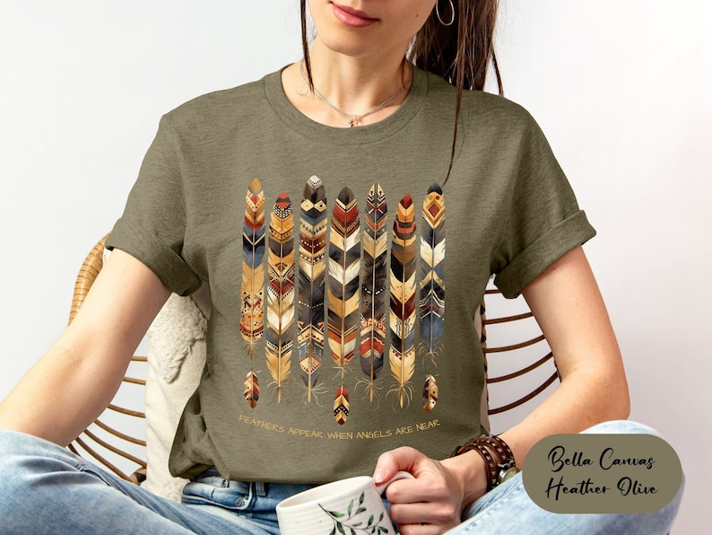 May include: A green t-shirt with a design of colorful feathers and the text "Feathers appear when angels are near".