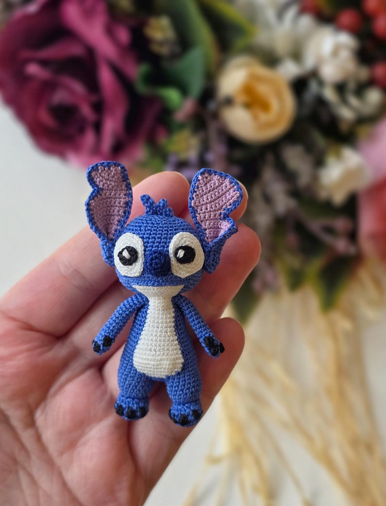 Handmade mini amigurumi Stitch doll crocheted with blue and white yarn, cute miniature crochet toy held in hand
