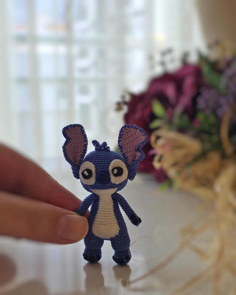 Handmade mini amigurumi Stitch doll crocheted with blue and white yarn, cute miniature crochet toy held in hand