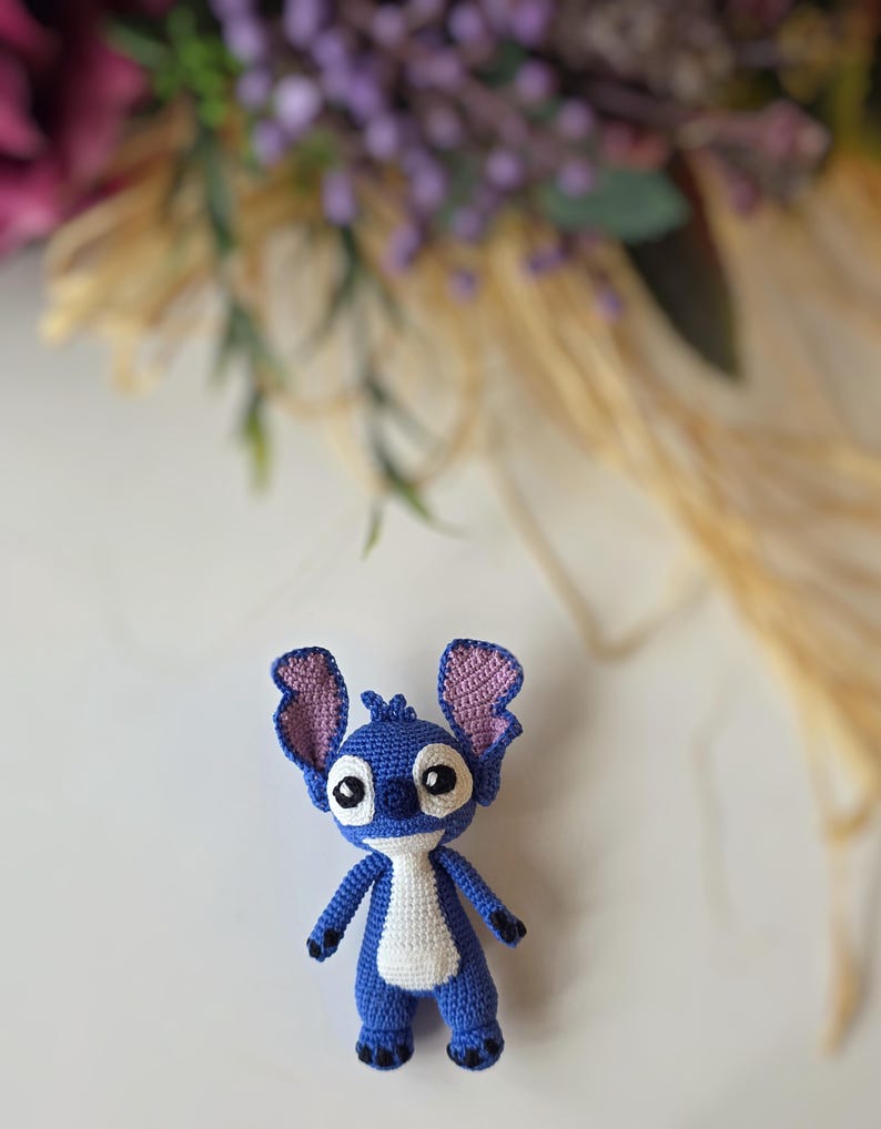Handmade mini amigurumi Stitch doll crocheted with blue and white yarn, cute miniature crochet toy held in hand