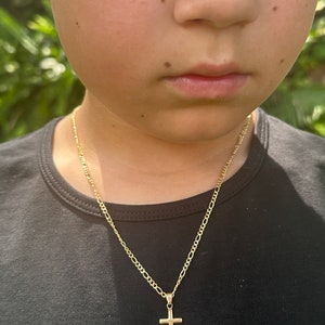 May include: A gold chain necklace with a small gold cross pendant.