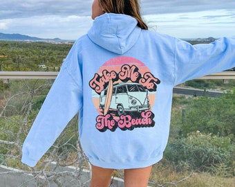 May include: A light blue hoodie with a vintage-style graphic on the back. The graphic features a retro van with a surfboard and the text "Take Me To The Beach".
