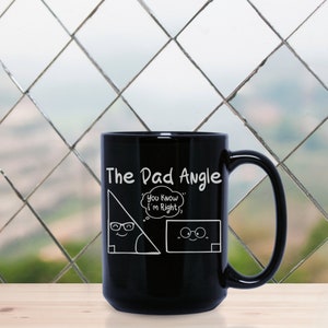 May include: Black ceramic mug with a white design of a right triangle with a face and glasses. The triangle is saying "You know I'm right." in a thought bubble. The text "The Dad Angle" is above the triangle.