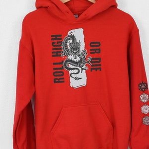 May include: Red hooded sweatshirt with a black dragon graphic and the text "Roll High or Die". The sweatshirt has a pocket on the front and a series of dice printed on the sleeve.