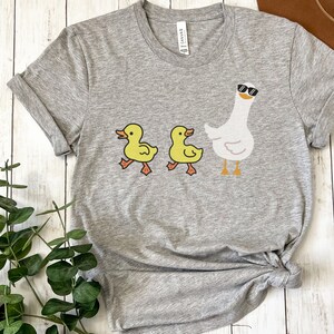 BELLA AND CANVAS T SHIRT WITH A CUTE DESIGN OF TWO DUCKS AND THEN A GOOSE.  AVAILABLE IN DARK GREY HEATHER, HEATHER MAUVE, NAVY, BLACK, ATHLETIC HEATHER AND HEATHER SLATE.