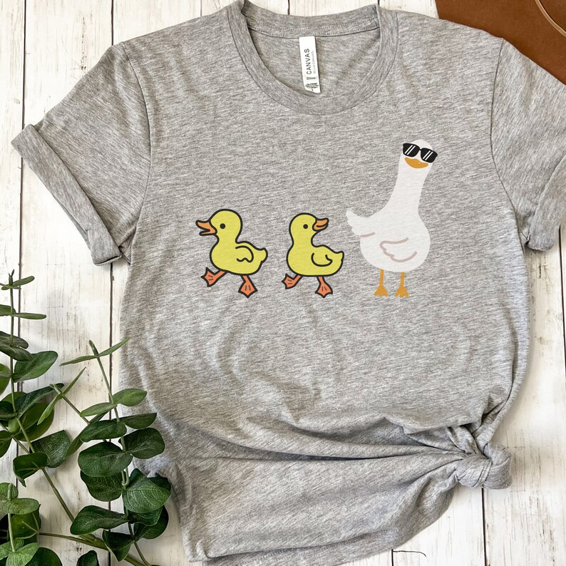 BELLA AND CANVAS T SHIRT WITH A CUTE DESIGN OF TWO DUCKS AND THEN A GOOSE.  AVAILABLE IN DARK GREY HEATHER, HEATHER MAUVE, NAVY, BLACK, ATHLETIC HEATHER AND HEATHER SLATE.
