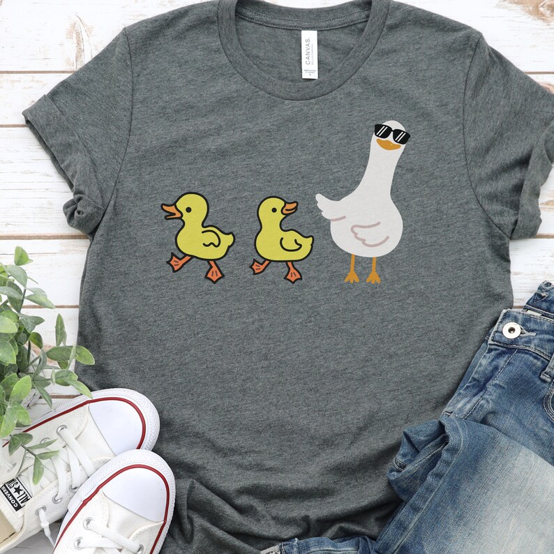 BELLA AND CANVAS T SHIRT WITH A CUTE DESIGN OF TWO DUCKS AND THEN A GOOSE.  AVAILABLE IN DARK GREY HEATHER, HEATHER MAUVE, NAVY, BLACK, ATHLETIC HEATHER AND HEATHER SLATE.
