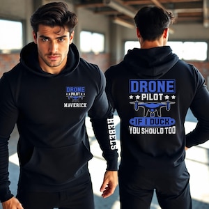 May include: Black hoodie with blue text that reads "DRONE PILOT" and "MAVERICK" on the front. The back of the hoodie has the text "DRONE PILOT" and "IF I DUCK YOU SHOULD TOO". The left sleeve has the word "HEBELS".