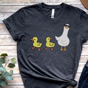 BELLA AND CANVAS T SHIRT WITH A CUTE DESIGN OF TWO DUCKS AND THEN A GOOSE.  AVAILABLE IN DARK GREY HEATHER, HEATHER MAUVE, NAVY, BLACK, ATHLETIC HEATHER AND HEATHER SLATE.
