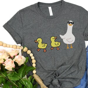 BELLA AND CANVAS T SHIRT WITH A CUTE DESIGN OF TWO DUCKS AND THEN A GOOSE.  AVAILABLE IN DARK GREY HEATHER, HEATHER MAUVE, NAVY, BLACK, ATHLETIC HEATHER AND HEATHER SLATE.