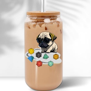 May include: A clear glass jar with a bamboo lid and a straw. The jar is filled with a light brown liquid and has a sticker on the front featuring a cartoon pug wearing sunglasses and surrounded by colorful dice.
