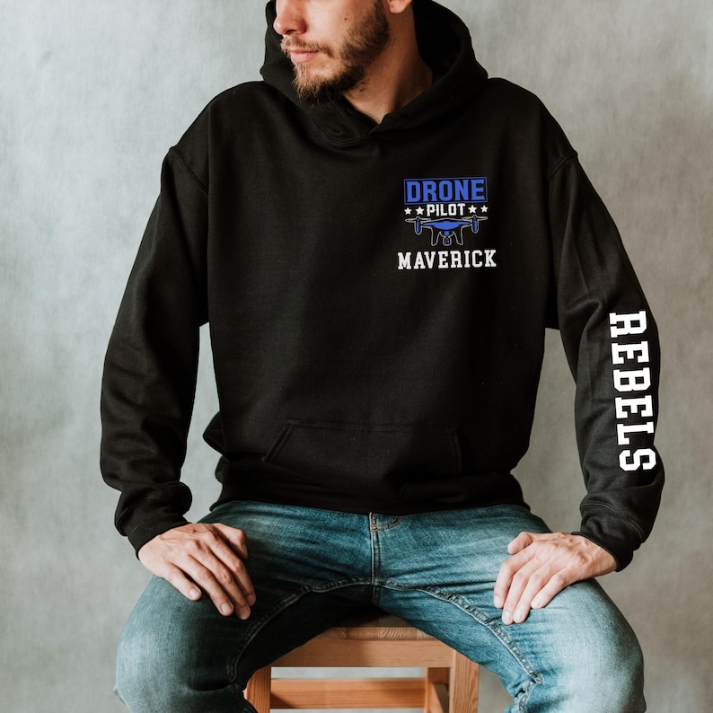 May include: Black hoodie with a front pocket and a blue and white graphic that reads "DRONE PILOT" above a drone illustration and the word "MAVERICK". The right sleeve has the word "REBELS" in white.