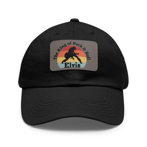 May include: Black baseball cap with a vintage-style patch featuring a silhouette of Elvis Presley playing guitar with the text "The King of Rock & Roll Elvis".