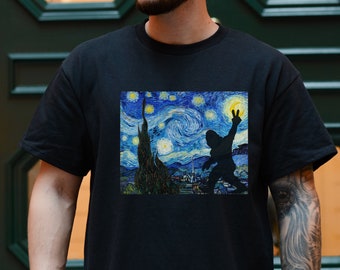 Może przedstawiać: Czarny t-shirt z nadrukiem graficznym Nocy Gwiezdnej Van Gogha, z sylwetką osoby pokazującej znak pokoju. Projekt wykorzystuje odcienie niebieskiego, żółtego i zielonego.