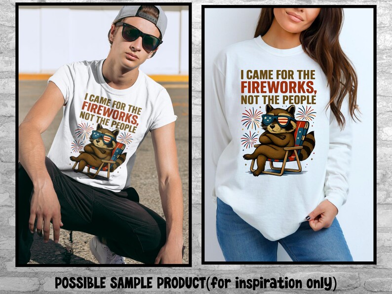 Op de afbeelding: Wit T-shirt en longsleeve shirt met een afbeelding van een wasbeer met een zonnebril die in een strandstoel zit. De tekst luidt: "I CAME FOR THE FIREWORKS, NOT THE PEOPLE." Het ontwerp bevat vuurwerk en patriottische kleuren.