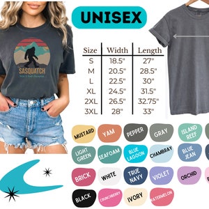 K&ouml;nnte beinhalten: Ein Unisex-T-Shirt mit einem Vintage-Grafikdruck eines Sasquatch, der vor einem Sonnenuntergang steht. Das Shirt ist in verschiedenen Farben erh&auml;ltlich, darunter Senf, Yam, Pfeffer, Grau, Inselriff, Moos, Hellgr&uuml;n, Schaum, Blauer Lagune, Chambray, Jeansblau, Denim, Ziegel, Wei&szlig;, Dunkelblau, Violett, Orchidee, Bl&uuml;te, Schwarz, Crunchberry, Elfenbein und Wassermelone. Das Shirt ist in den Gr&ouml;&szlig;en S, M, L, XL, 2XL und 3XL erh&auml;ltlich. Die Gr&ouml;&szlig;entabelle zeigt die Breite und L&auml;nge jeder Gr&ouml;&szlig;e in Zoll.