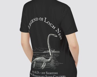 May include: Black polo shirt with a white graphic of the Loch Ness Monster and the text "The Legend of Loch Ness 565 A.D. - 1st Sighting by Missionary Saint Columba"