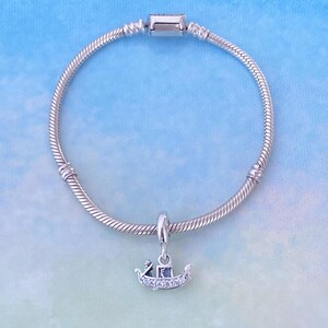 May include: A silver charm bracelet with a silver gondola charm with clear cubic zirconia stones.