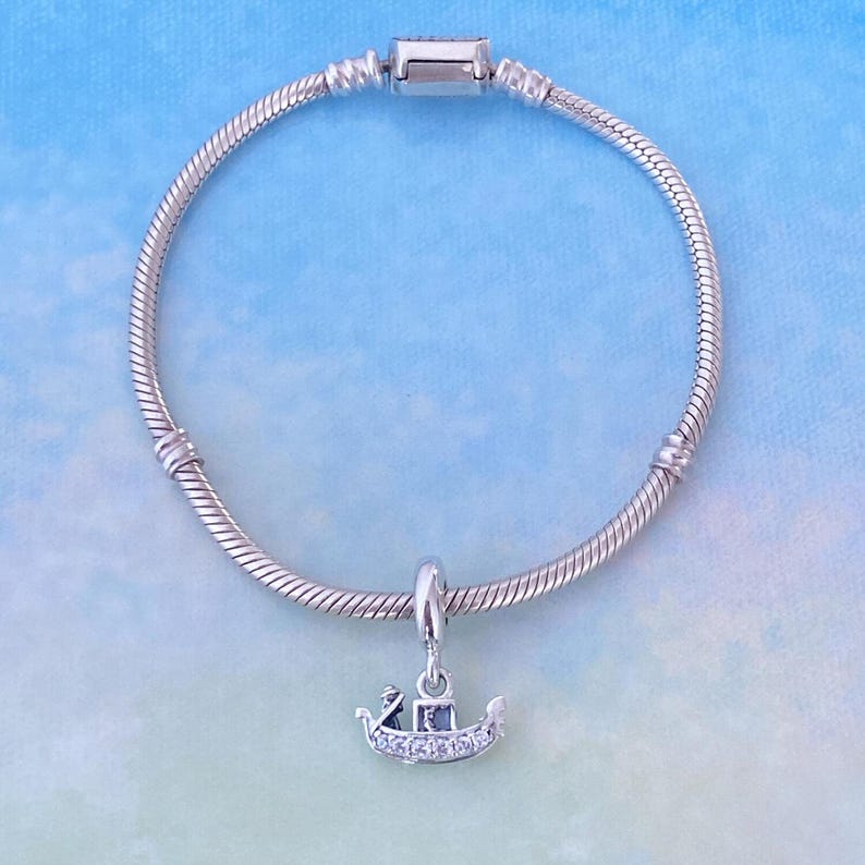 May include: A silver charm bracelet with a silver gondola charm with clear cubic zirconia stones.