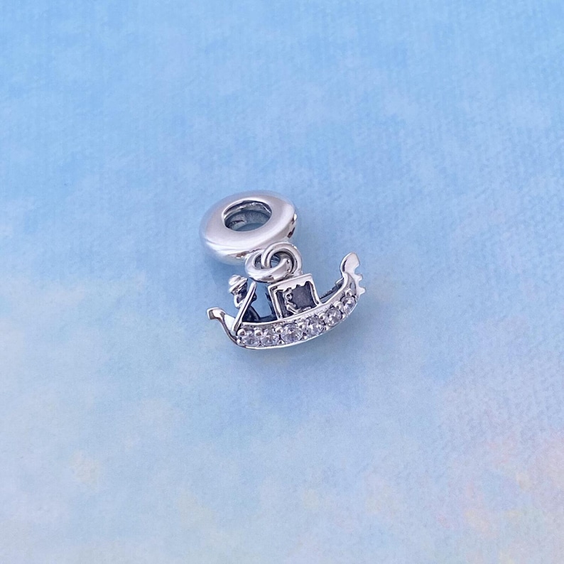 May include: A silver charm in the shape of a gondola with clear crystal accents.